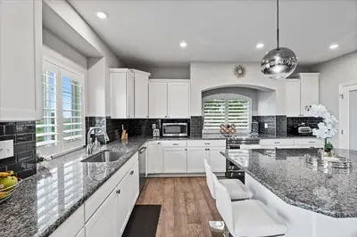 a kitchen with white cabinets and marble counter tops at The Retreat at Buffalo Run Golf Course - Commerce City in Henderson