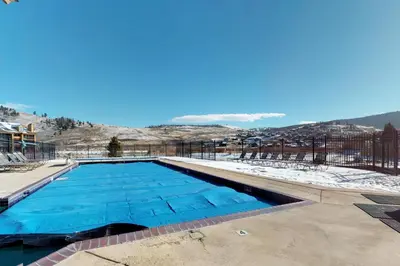 a swimming pool with snowy mountains in the background at Silver Lodge A & B in Granby