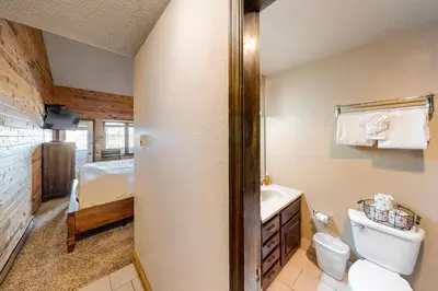 a bathroom with a toilet and a sink and a bed at Silver Lodge A in Granby