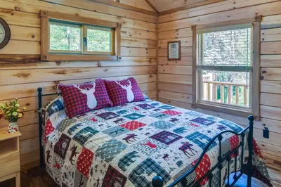 a log cabin bedroom with a quilt on a bed at Private Hot Tub and Pond Conifer Log Cabin in Conifer