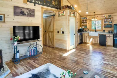 a living room with a flat screen tv on a wooden wall at Private Hot Tub and Pond Conifer Log Cabin in Conifer