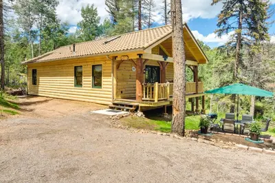 a log cabin in the woods with a patio at Private Hot Tub and Pond Conifer Log Cabin in Conifer