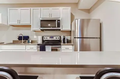 a kitchen with white cabinets and a stainless steel refrigerator at Central Park - 28th Place Apt in Aurora