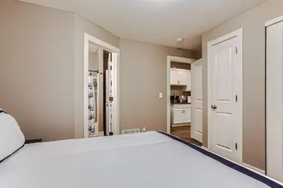 a bedroom with a white bed and a kitchen at Central Park - 28th Place Apt in Aurora