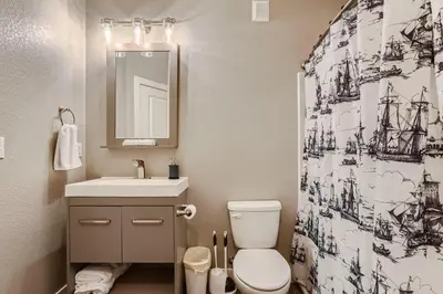 a bathroom with a toilet and a sink and a shower curtain at Central Park - 28th Place Apt in Aurora
