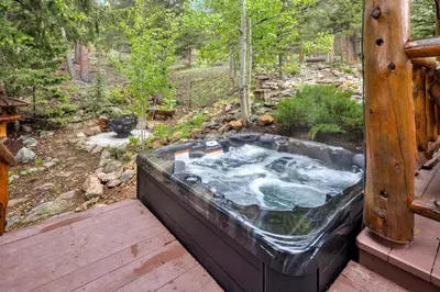 a hot tub sitting on a deck in the woods at Aspen Suite - Hot Tub, Minutes to RMNP, Walking Distance to Mary's Lake in Estes Park