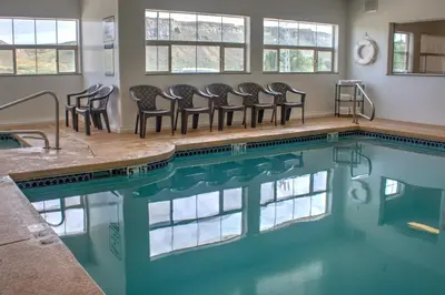 a swimming pool with chairs sitting around it at Allington Inn & Suites Kremmling in Kremmling
