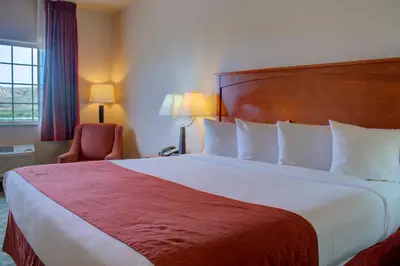 a hotel room with a large bed and a chair at Allington Inn & Suites Kremmling in Kremmling