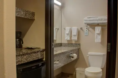 a bathroom with a toilet and a sink with a mirror at Allington Inn & Suites Kremmling in Kremmling