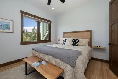 a bedroom with a bed with a table and a window at Hay Meadow Lodge townhouse in Fraser
