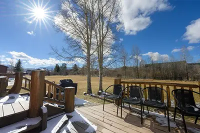 a deck with chairs and a tree and the sun at 701B Quail in Fraser