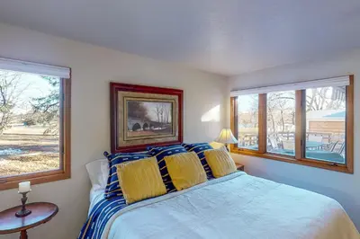 a bedroom with a bed and two windows at Work and Play! Spacious Lake-View Home in Greeley in Greeley