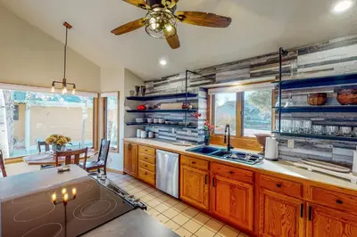 a kitchen with wooden cabinets and a ceiling fan at Work and Play! Spacious Lake-View Home in Greeley in Greeley