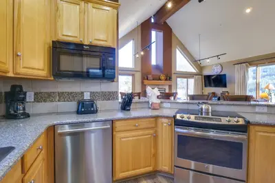 a kitchen with wooden cabinets and stainless steel appliances at 1 Mi to Keystone Lifts Hot Tub Haven with Mtn Views in Keystone