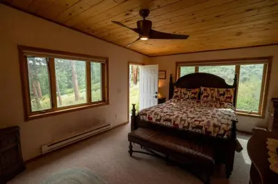 a bedroom with a bed and a ceiling fan at Warm Woodland Getaway with Land in Red Feather Lakes