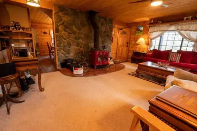 a living room with a stone fireplace and a red couch at Warm Woodland Getaway with Land in Red Feather Lakes
