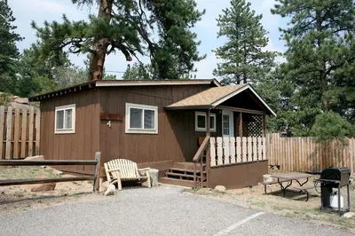 a small cabin with a bench and a fence at Lazy R Cottages- 4 cabin in Estes Park