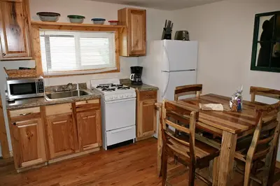 a kitchen with a table and a white refrigerator at Lazy R Cottages- 4 cabin in Estes Park