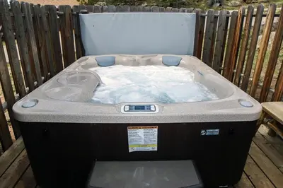 a hot tub sitting on a deck with a fence at Lazy R Cottages- 4 cabin in Estes Park