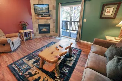 a living room with a couch and a table and a fireplace at Fawn Valley Inn- 297 condo in Estes Park