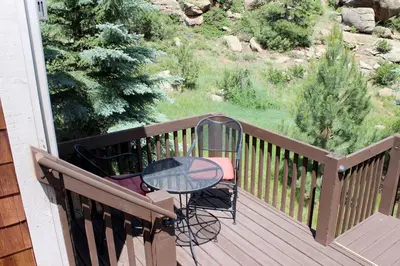 a wooden deck with a table and chairs on it at Sunnyside Knoll- 18 cabin in Estes Park
