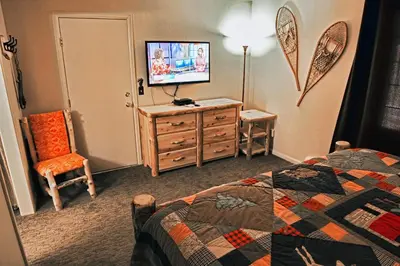 a bedroom with a bed and a dresser with a television at Fawn Valley Inn- 284 condo in Estes Park