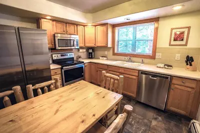 a kitchen with a wooden table and stainless steel appliances at Timber Creek Chalets- 9 chalet in Estes Park