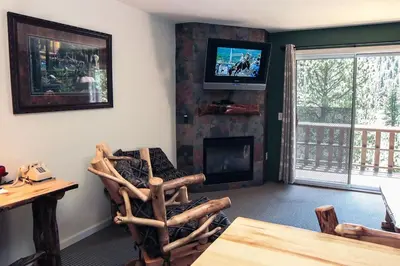 a living room with a fireplace and a tv on the wall at Fawn Valley Inn- 280 condo in Estes Park