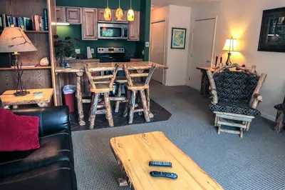 a living room with a kitchen with a table and chairs at Fawn Valley Inn- 280 condo in Estes Park