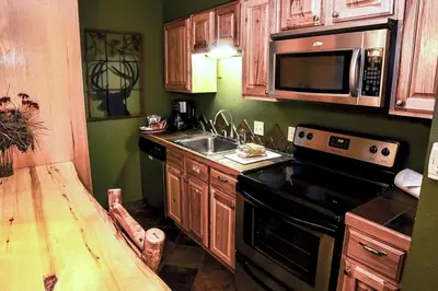 a kitchen with wooden cabinets and a sink and a microwave at Fawn Valley Inn- 280 condo in Estes Park