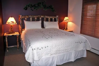 a bedroom with a large bed with two lamps at Fawn Valley Inn- 280 condo in Estes Park