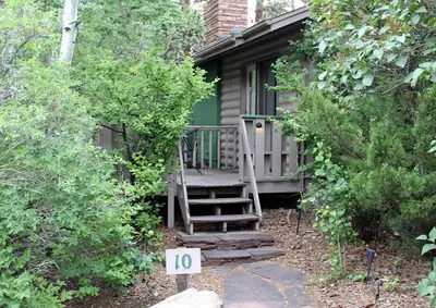 a small cabin with a porch and a wooden staircase at Sunnyside Knoll- 10 studio in Estes Park