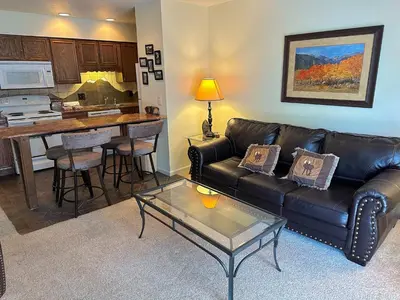 a living room with a leather couch and a table at Fawn Valley Inn- 292 apts in Estes Park