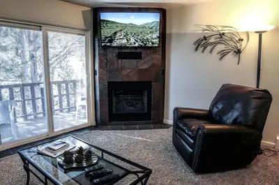 a living room with a chair and a fireplace at Fawn Valley Inn- 292 apts in Estes Park