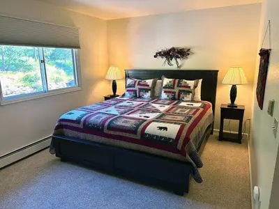 a bedroom with a bed with two lamps and two windows at Fawn Valley Inn- 292 apts in Estes Park