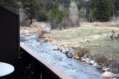 a river with rocks on the side of a house at Fawn Valley Inn- 210 condo in Estes Park