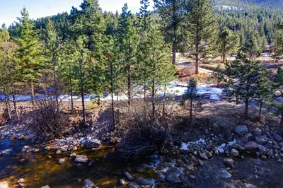 a stream in the woods with trees and snow at Fawn Valley Inn- 210 condo in Estes Park