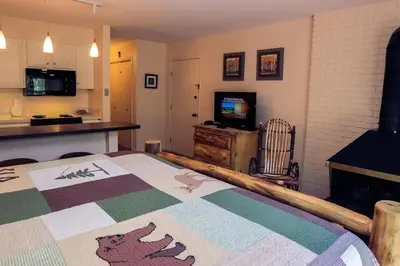a room with a bed and a kitchen and a television at Fawn Valley Inn- 278 condo in Estes Park