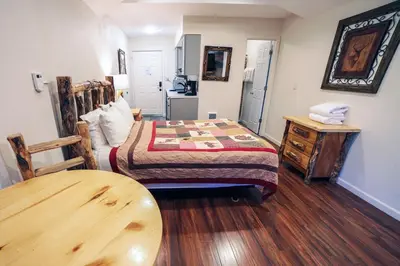 a bedroom with a bed and a wooden table at Fawn Valley Inn- 296 apts in Estes Park
