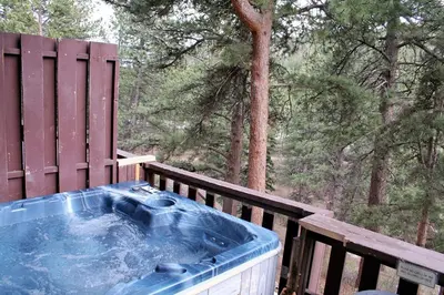 a hot tub on a wooden deck with trees at Fawn Valley Inn- 296 apts in Estes Park