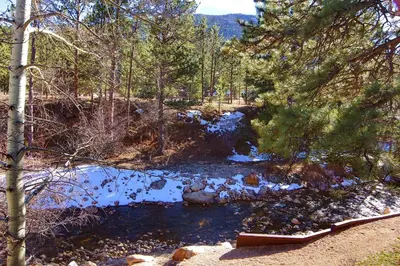 a river with snow on the ground and trees at Fawn Valley Inn- 242 apts in Estes Park