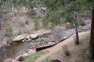 a stream of water with rocks and trees at Fawn Valley Inn- 242 apts in Estes Park
