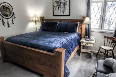 a bedroom with a wooden bed with a blue comforter at Fawn Valley Inn- 242 apts in Estes Park