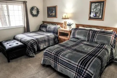 a bedroom with two beds and a chair and a window at Fawn Valley Inn- 242 apts in Estes Park