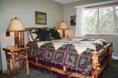 a bedroom with a bed with a quilt on it at Fawn Valley Inn- 306 apts in Estes Park