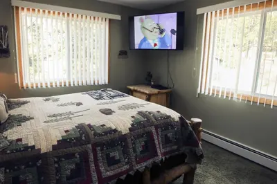 a bedroom with a bed and a tv on the wall at Fawn Valley Inn- 306 apts in Estes Park