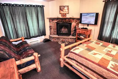 a bedroom with a fireplace and a bed and a tv at Lazy R Cottages- 7B cottage in Estes Park