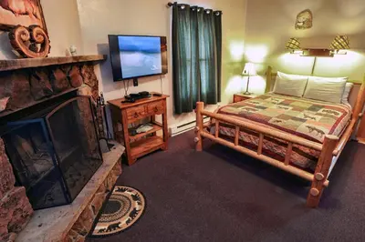 a bedroom with a bed and a fireplace and a television at Lazy R Cottages- 7B cottage in Estes Park