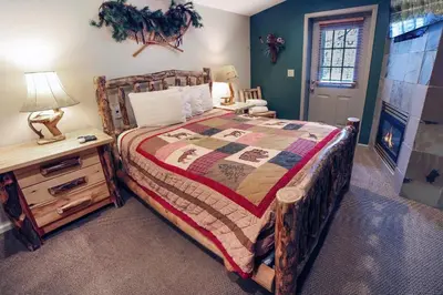 a bedroom with a bed and a table with a lamp at Fawn Valley Inn- 107 condo in Estes Park