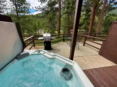 a hot tub on a deck with a grill at Fawn Valley Inn- 107 condo in Estes Park